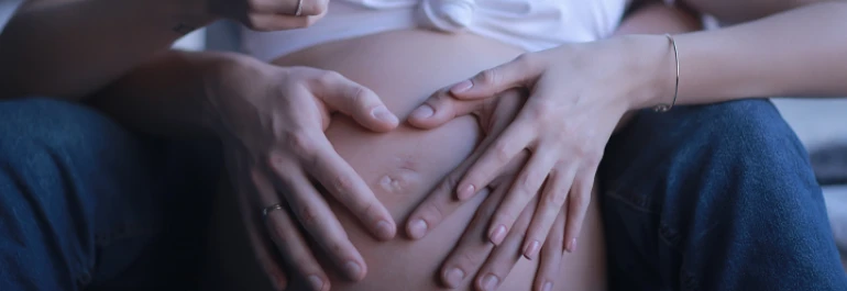  Una pareja coloca sus manos sobre un vientre de embarazo. 
