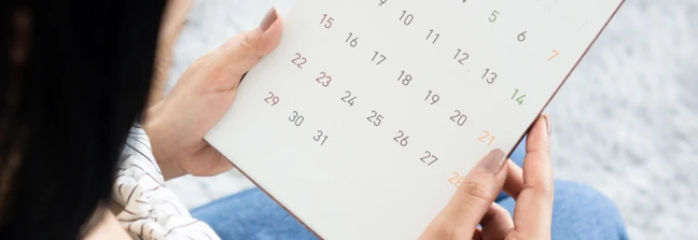  Una persona sostiene un calendario mientras lo observa detenidamente. 
