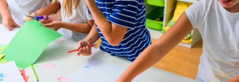  Niños realizando actividades de manualidades en una mesa. 