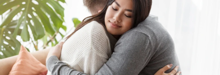  Dos personas se abrazan con expresión de tranquilidad y cariño. 