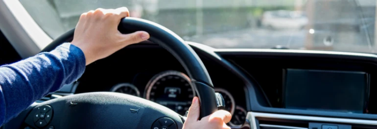  Una persona está conduciendo un automóvil con ambas manos en el volante. 