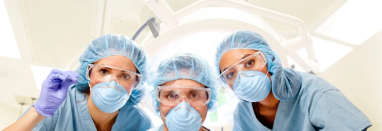  Tres profesionales de la salud con equipo de protección miran hacia la cámara en un entorno médico. 