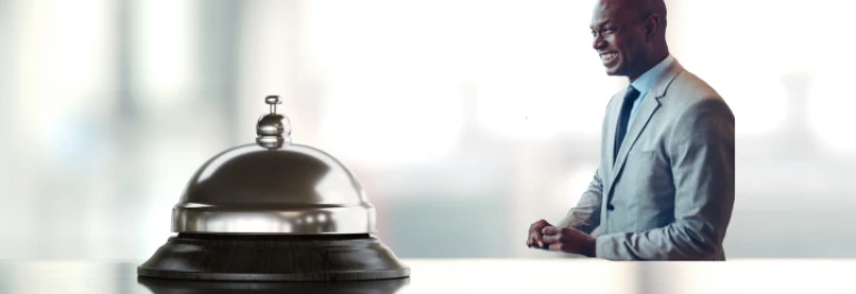  Un hombre sonriente de pie junto a una campana de recepción. 