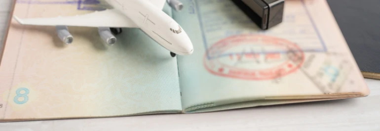  Un avión en miniatura está sobrepasando un pasaporte abierto con sellos. 
