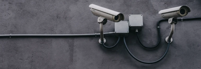  Cámaras de seguridad sobre pared de  hormigón gris enfocando hacia la derecha 