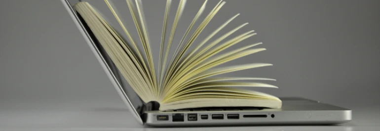  Un libro está colocado sobre el teclado de una laptop abierta. 