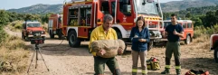  Bombero haciendo pruebas físicas con camiones de bombero detrás 