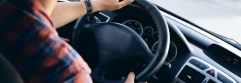  Hombre con camisa de cuadros y reloj negro sujetando volante de coche 
