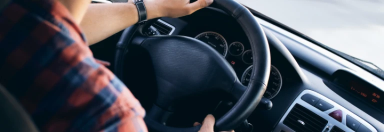  Hombre con camisa de cuadros y reloj negro sujetando volante de coche 