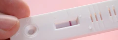  Persona sujetando un test de embarazo con una raya roja 
