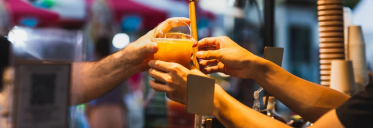  persona entregando a otra una bebida en la barra 