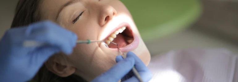  Una dentista con guantes azules está examinando los dientes de una paciente. 