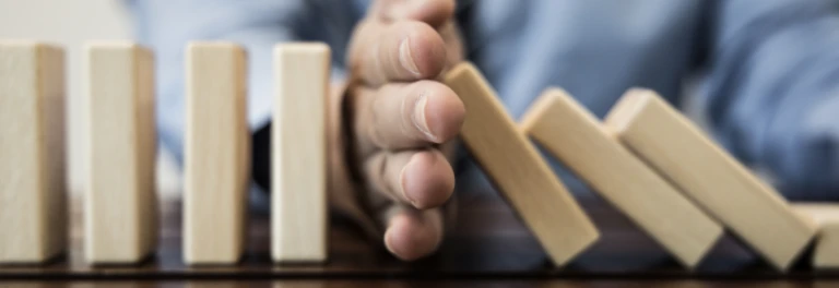  mano interrumpiendo efecto dominó en la mesa 