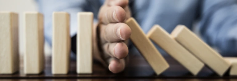  mano interrumpiendo efecto dominó en la mesa 