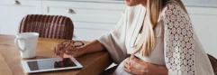  Mujer embarazada trabajando frente a ipad que está en una mesa de madera 