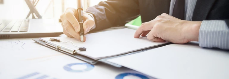  Una persona está escribiendo en un papel sobre una mesa con gráficos. 