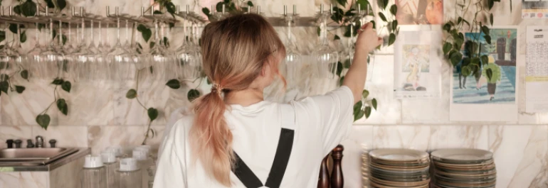  Chica rubia acomodando copas en la barra de un bar 