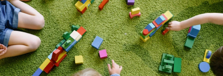  Niños jugando con bloques de colores sobre una alfombra verde. 