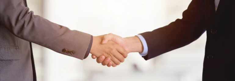  Dos personas en trajes de negocios se dan la mano. 